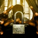 une personne tenant un cadenas devant une fenêtre