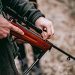 une personne chargeant un fusil de sniper marron et noir
